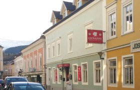 Giovanni, © privat Straßenszene mit bunten Gebäuden und einem Schild mit der Aufschrift 'Giovanni'.