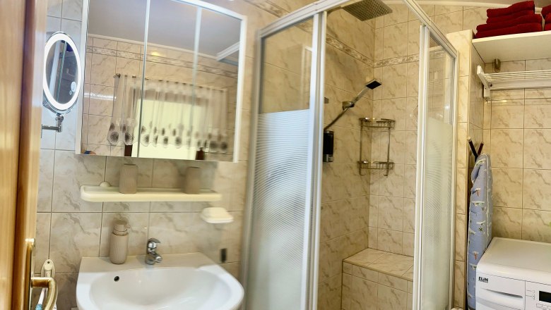 Ferienwohnung Schindlegger, © Familie Schindlegger Badezimmer mit Dusche, Waschbecken, Spiegel und Waschmaschine.