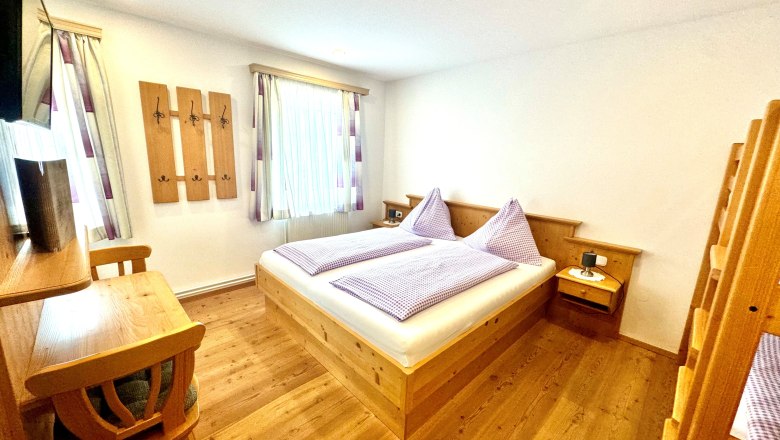 Urlaub am Moaserhof, © Familie Buber Ein gemütliches Schlafzimmer mit Holzmöbeln, einem Doppelbett und einem Etagenbett.