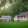 Mendlingbauer, © Mendlingbauer Zwei traditionelle Bauernhäuser in einer grünen, bewaldeten Landschaft.