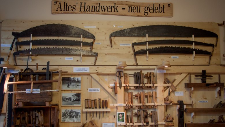 Altes Handwerk - neu gelebt, © Rene Jagersberger Ausstellung von alten Handwerkzeugen an einer Holzwand mit dem Schild 'Altes Handwerk - neu gelebt'.
