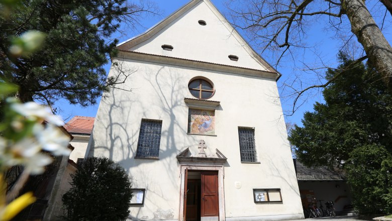 Kapuzinerkirche, © schwarz-koenig.at Fassade der Kapuzinerkirche mit Eingang und Fenstern, umgeben von Bäumen.