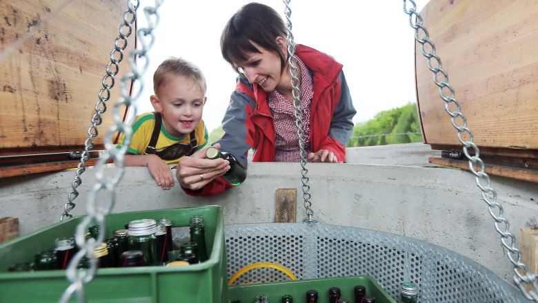 Mostbrunnen Reinsberg, © weinfranz.at Ein Kind und eine Frau betrachten Flaschen in einem Brunnen.