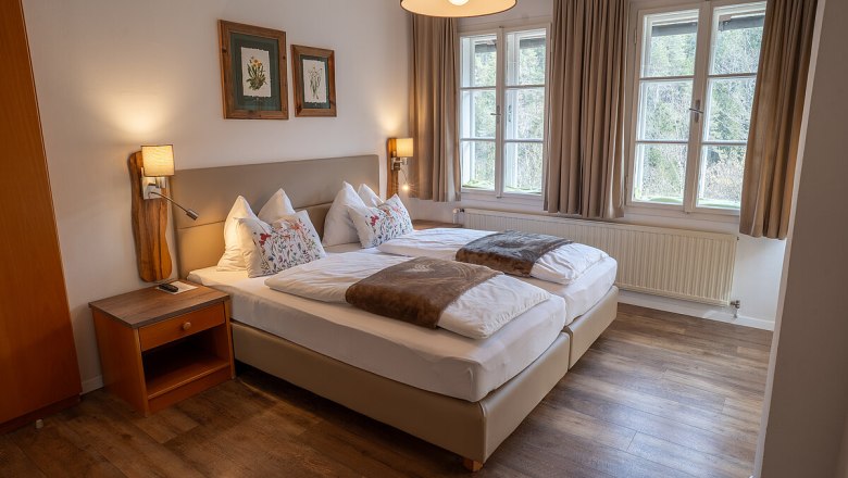 Fastenhaus Maria Seesal, © Fasthaus Maria Seesal Ein gemütliches Schlafzimmer mit zwei Einzelbetten, Holzboden und großen Fenstern mit Blick auf die Natur.