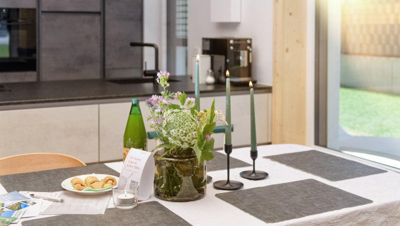 Gratzenthal Hollenstein, © schubert-photography Ein gedeckter Tisch in einer modernen Küche mit Blumen, Kerzen und Snacks.