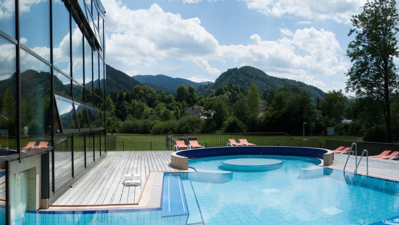 Ybbstaler Solebad, © Rene Jagersberger Außenbereich des Ybbstaler Solebads mit Pool und Liegestühlen, umgeben von grünen Hügeln und Bäumen.
