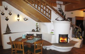 Jausenstation Putzmühle, © Jausenstation Putzmühle Gemütlicher Innenraum mit Kamin, Holztisch und Treppe.