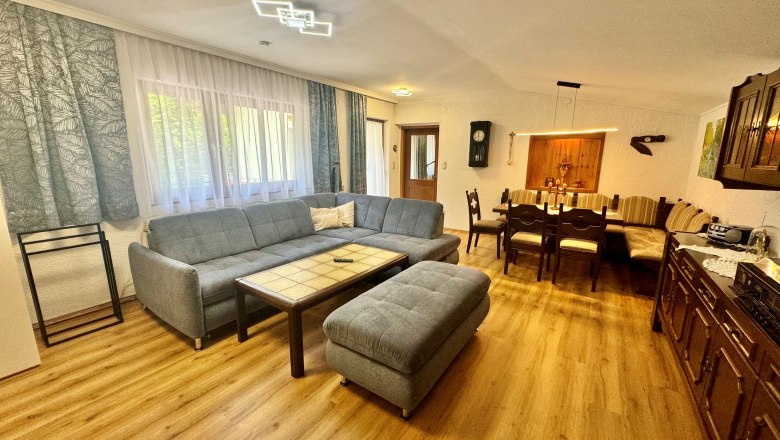 Ferienwohnung Schindlegger, © Familie Schindlegger Wohnzimmer einer Ferienwohnung mit blauem Sofa und einer zusätzlichen Eckbank mit Tisch