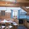 Küche, © Ferienhaus Hintereck Rustikale Küche mit Holzmöbeln, Esstisch und Stühlen, Herd, Spüle und Fenster mit karierten Vorhängen.