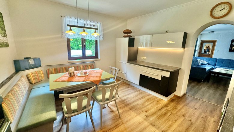 Ferienwohnung Schindlegger, © Familie Schindlegger Gemütliche Küche mit Esstisch und Eckbank, daneben eine moderne Küchenzeile. Im Hintergrund ein Wohnzimmer mit blauer Couch.