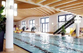 Ybbstaler Solebad, © Ybbstaler Solebad Innenansicht eines Schwimmbads mit Holzdecke und großen Fenstern.
