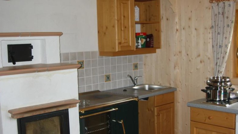 Feriendorf Lassing-Hochkar, © Feriendorf Lassing Küche in einem rustikalen Stil mit Holzschränken, einem Ofen und einem Herd.