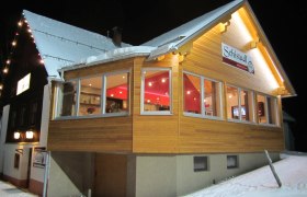 Schistadl, © Helmel Franz Ein beleuchtetes Gebäude im Schnee mit dem Schild 'Schistadl'.