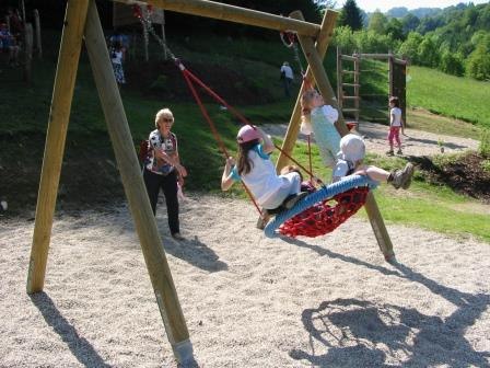 Spielplatz, © Bernhard Hofecker Kinder schaukeln auf einem Spielplatz in einer Nestschaukel.