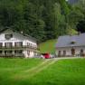 Mendlingbauer, © Mendlingbauer Zwei traditionelle Gebäude in einer grünen, bewaldeten Umgebung.