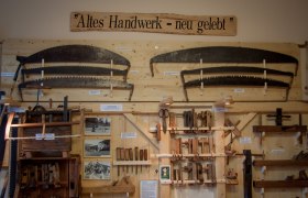 Altes Handwerk - neu gelebt, © Rene Jagersberger Ausstellung von alten Handwerkzeugen an einer Holzwand mit dem Schild 'Altes Handwerk - neu gelebt'.