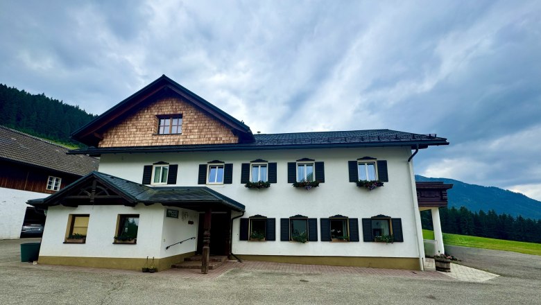 Urlaub am Moaserhof, © Familie Buber Ein traditionelles zweistöckiges Bauernhaus mit weißen Wänden und schwarzen Fensterläden.