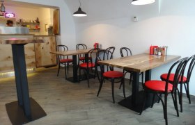 J's American Burgers, © privat Innenansicht eines modernen Restaurants mit Holztischen und roten Stühlen.