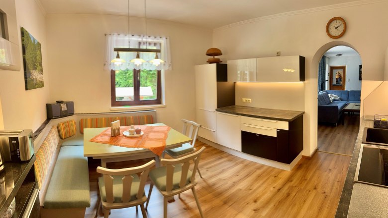 Ferienwohnung Schindlegger, © Familie Schindlegger Gemütliche Küche mit Esstisch und Eckbank, daneben moderne Küchenschränke. Im Hintergrund ein Wohnzimmer mit Sofa.