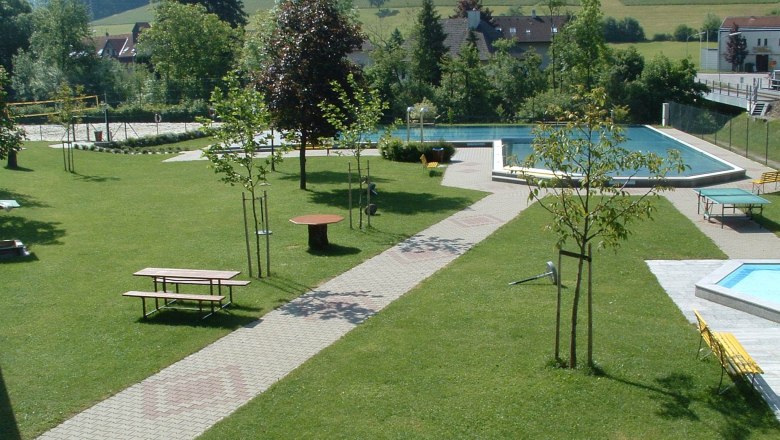 Gr&uuml;ne Parkanlage mit Schwimmbecken und Sitzb&auml;nken.