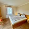 Gem&uuml;tliches Schlafzimmer mit Holzm&ouml;beln, Doppelbett und Schreibtisch.