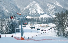 Skigebiet Forsteralm mit Sessellift und schneebedeckten Bäumen.