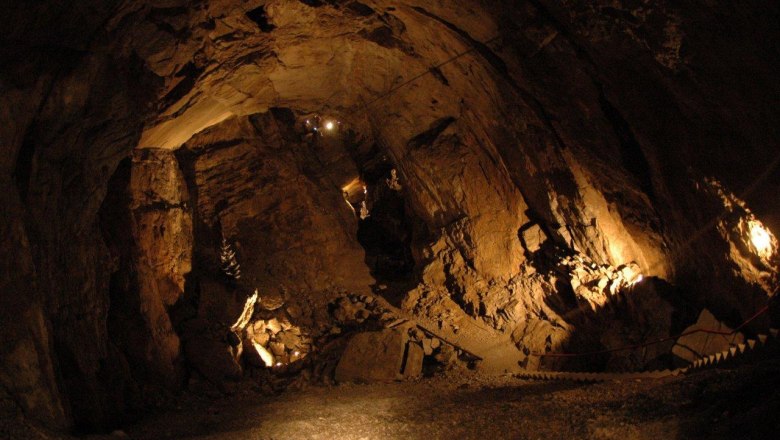 Innenansicht einer beleuchteten Höhle mit steinigen Wänden und einem schmalen Pfad.