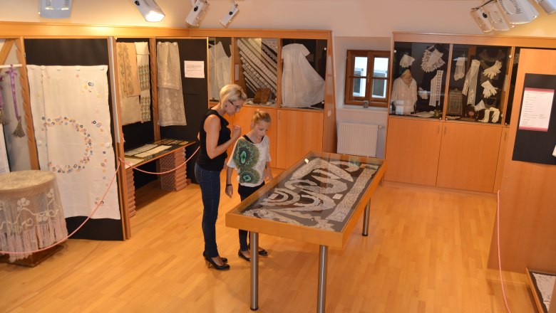 Zwei Personen betrachten Exponate in einem Handarbeitsmuseum.