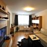 Modern eingerichtetes Wohnzimmer mit Sofa, Fernseher, Schreibtisch und Regalen.