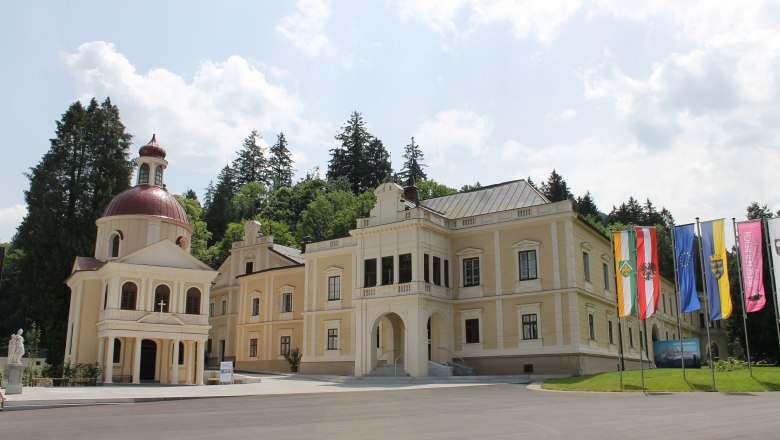Schloss Neubruck mit Kapelle und Fahnen im Vordergrund.