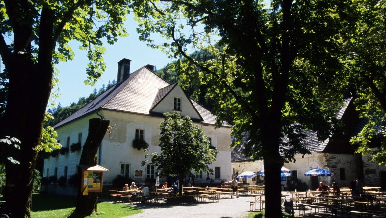 Ein Herrenhaus mit Biergarten im Gr&uuml;nen, umgeben von B&auml;umen.