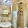 Badezimmer mit Dusche, Waschbecken, Spiegel und Waschmaschine.