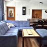 Gem&uuml;tliches Wohnzimmer mit blauer Couch, Holztisch und Essbereich in einer Ferienwohnung.