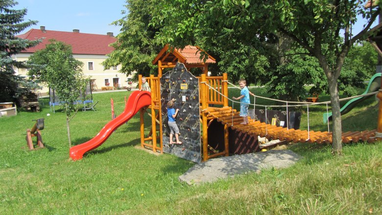 Spielplatz mit Klettergerüst, Rutsche und zwei Kindern beim Spielen.