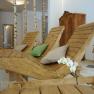 Innenansicht eines Wellnessbereichs mit Holzliegen, Kissen und Birkenst&auml;mmen.