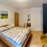 Ein Schlafzimmer mit einem Doppelbett, einem gelben Stuhl, einem Schrank.