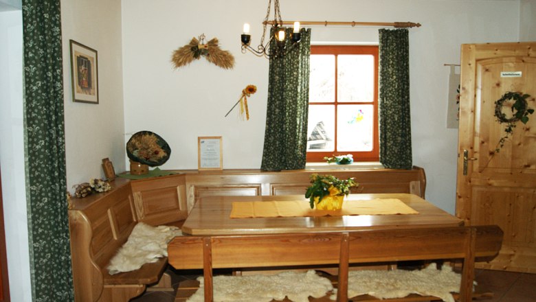 Gemütlicher Aufenthaltsraum mit Holzmöbeln, Tisch, Eckbank und Dekorationen an der Wand.