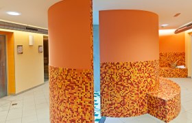 Innenansicht eines Wellnessbereichs mit orangefarbenen Mosaikfliesen und runden Wänden.