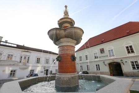 Kaiser Franz Josef Jubiläumsbrunnen vor einem Rathausgebäude.