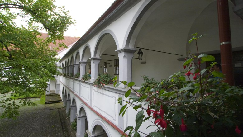 Ein zweist&ouml;ckiger Arkadengang mit wei&szlig;en B&ouml;gen und Blumen im Schloss Scheibbs.