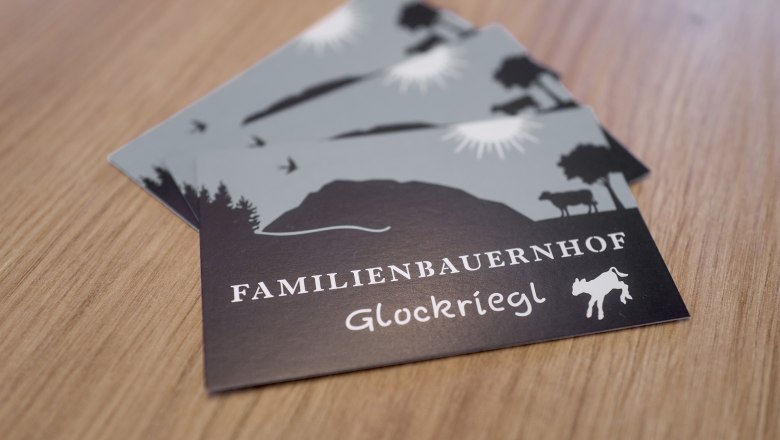 Postkarten mit dem Logo des Familienbauernhofs Glockriegl auf einem Holztisch.