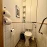 Kleines Badezimmer mit Toilette, wei&szlig;en Fliesen und einem Schrank.