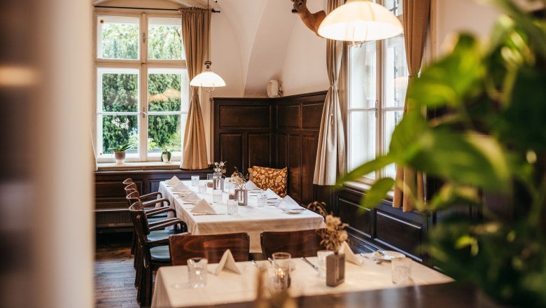 Gemütliches Restaurant mit gedecktem Tisch, Holzmöbeln und Hirschkopf an der Wand.