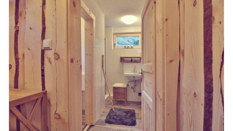 Innenansicht eines Badezimmers in einem Chalet mit Holzwänden und -türen, Waschbecken und kleinem Fenster.