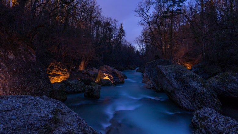 Nachtaufnahme der Erlaufschlucht mit beleuchteten Felsen und fließendem Wasser.