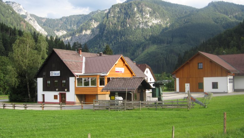 Ein Geb&auml;ude mit der Aufschrift 'Schistadl' vor einer Berglandschaft.
