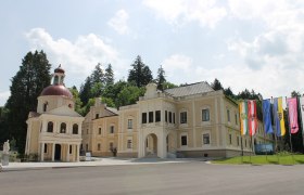 Schloss Neubruck mit Kapelle und Fahnen im Vordergrund.