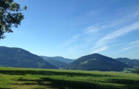 Landschaft mit grünen Hügeln und blauem Himmel.
