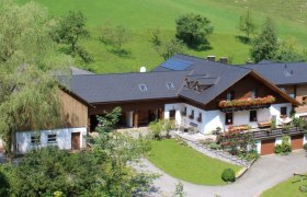 Luftaufnahme eines Bauernhofs mit gr&uuml;nem Dach und Blumendekorationen.