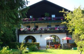 Ein traditionelles Gasthaus mit Holzbalkon und Blumen in Scheibbs, umgeben von einem gr&uuml;nen Garten.